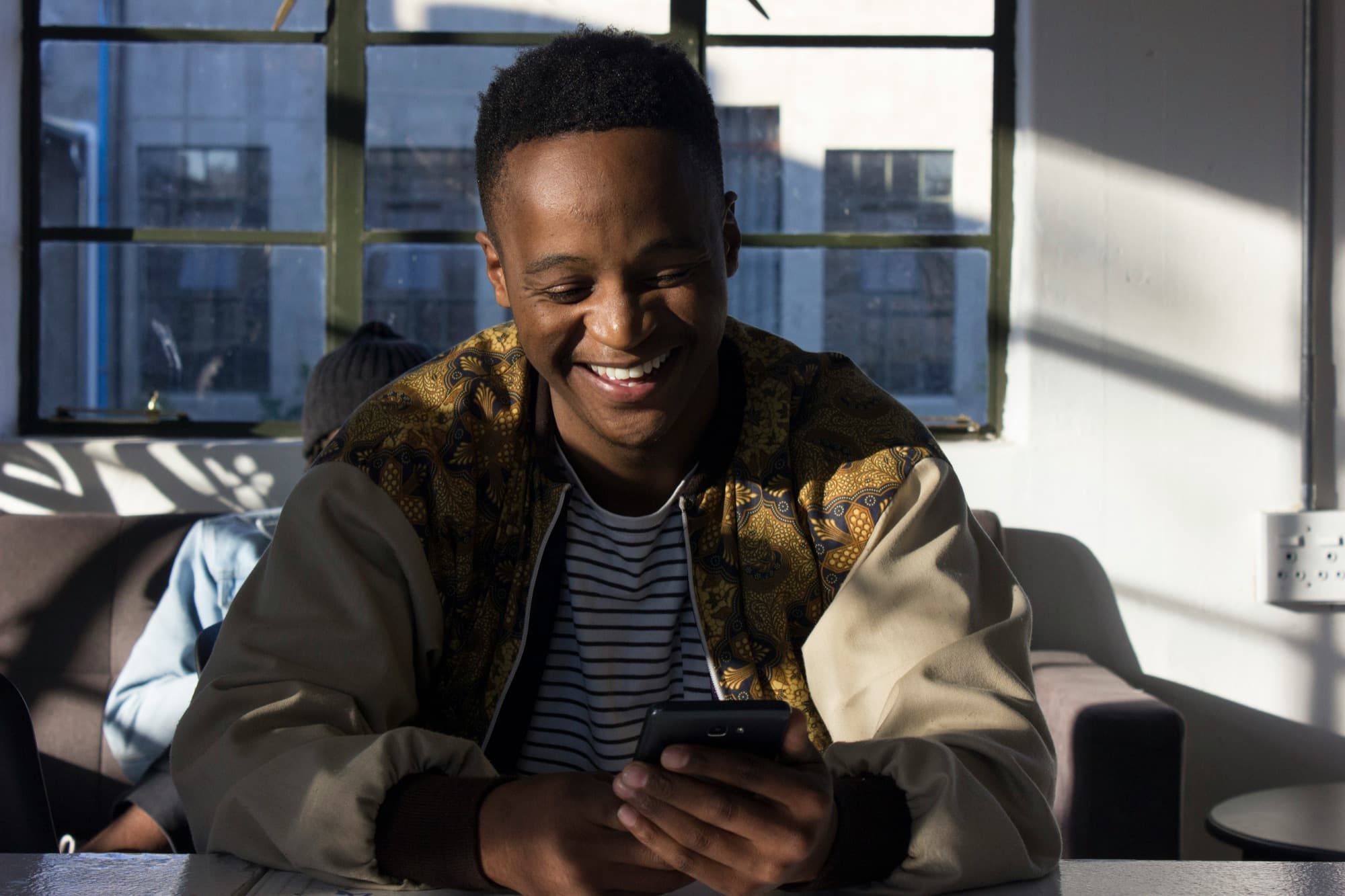 A South African business owner smiling at their phone